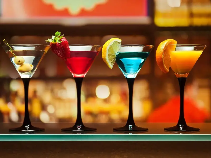 A row of different colored drinks in glasses.