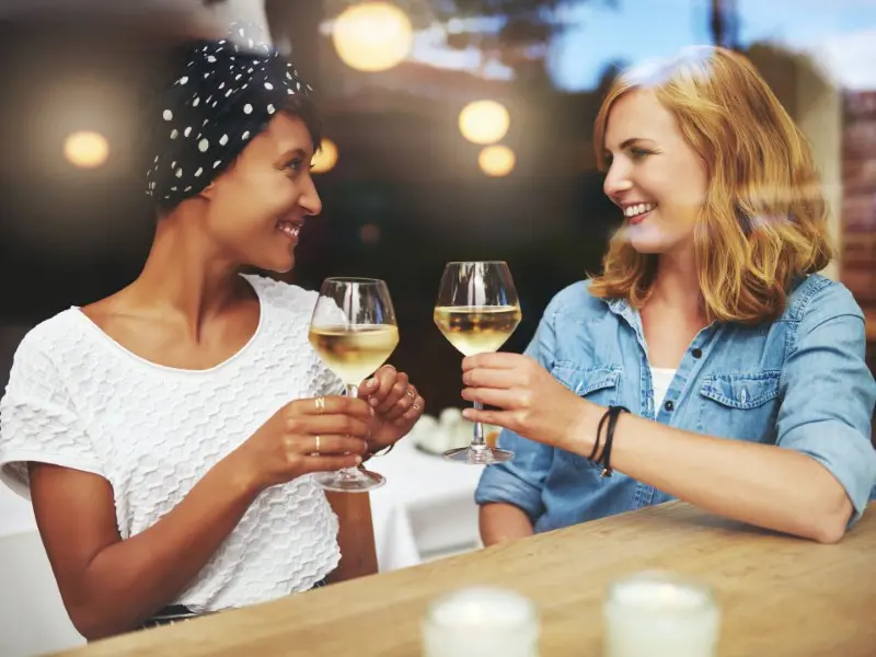 Two women are drinking wine at a table.