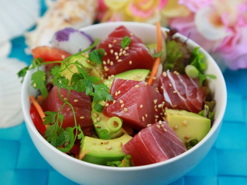 A bowl of salad with tuna, avocado and sesame seeds.