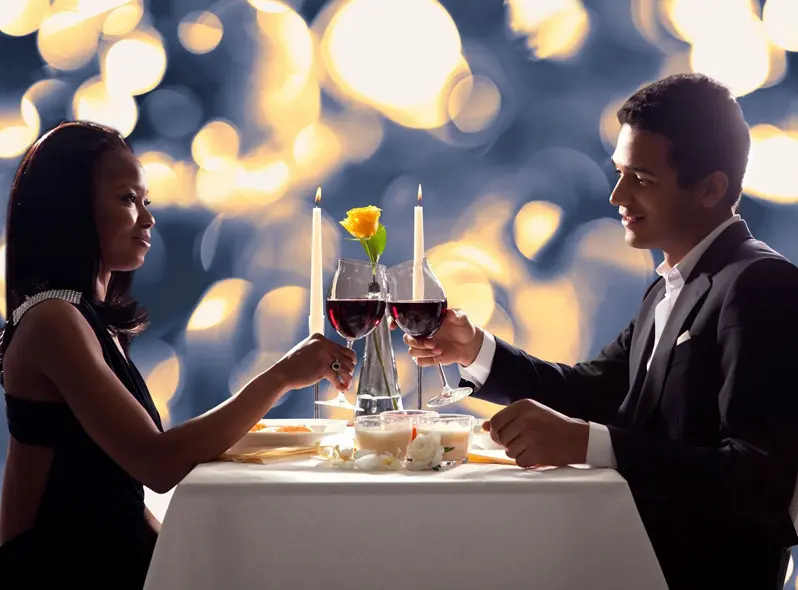 A man and woman holding hands at a table with wine.